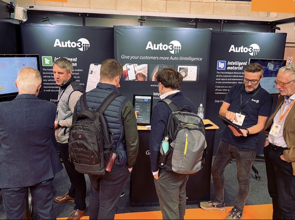 Visitors around the Auto3 touchscreen stand at a UK trade show