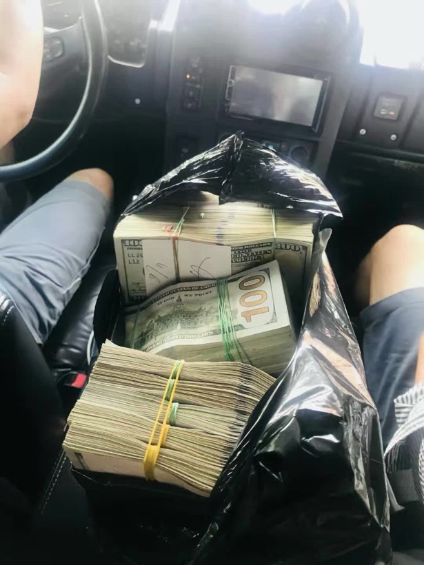 A bag of cash on the passenger seat of the car